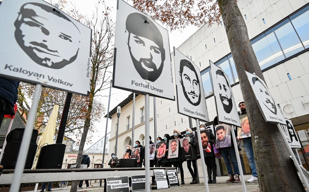 Angehörige der Opfer des rassistischen Anschlags von Hanau 2020 halten bei einer Mahnwache Fotos der Opfer.
