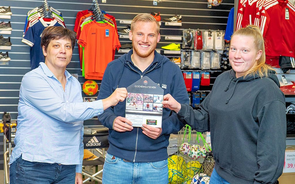 Jonas Weise vom Teamwork-Sporthaus F.C.Röder in Freyburg übergibt einen 100-Euro-Gutschein an die Gewinnerinnen der Tippspiel-Mannschaftswertung. Kathrin Gorn (l.) und Tochter Juliane, die beim FC RSK von Weise trainiert wird, nennen sich „Frauenpower“.