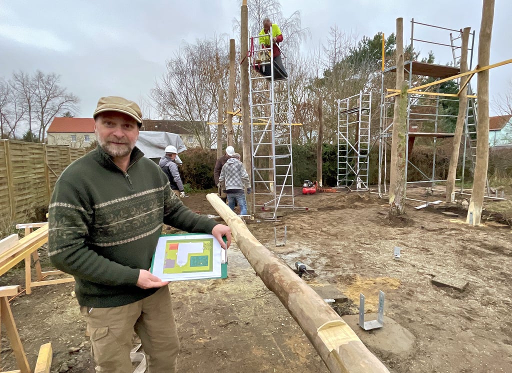 Der Storchenhof Loburg erhält eine Freiflugvoliere für Störche. Geschäftsführer Michael Kaatz zeigt den Grundriss der neuen Anlage, die aus Robinienstämmen errichtet wird. Im Hintergrund ragen erste Stämme in die Höhe.