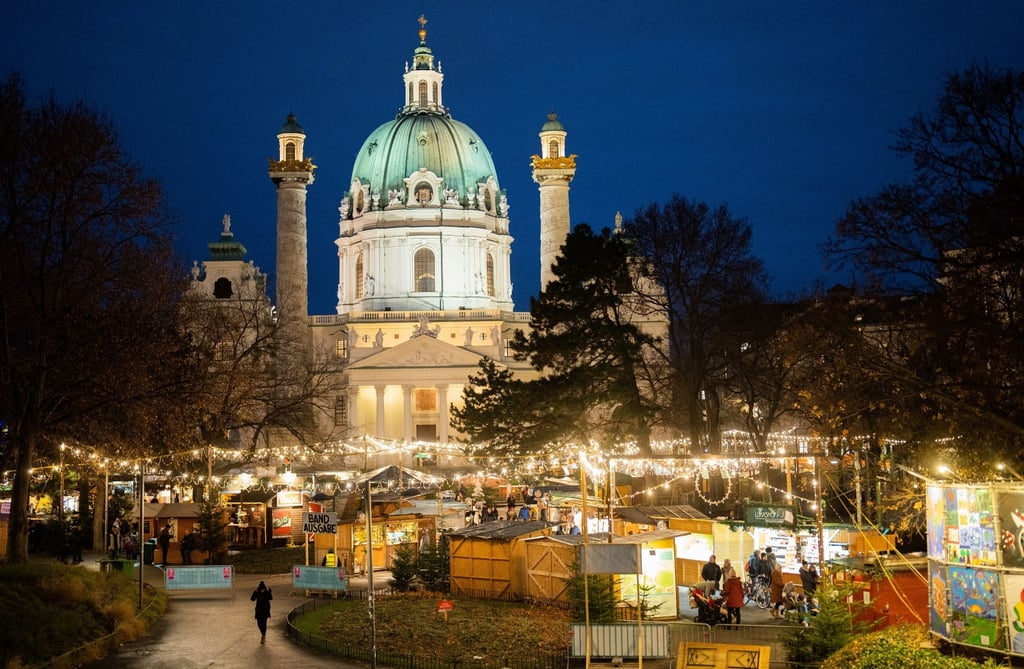 Menschen besuchen den Christkindlmarkt am Karlsplatz in Wien.