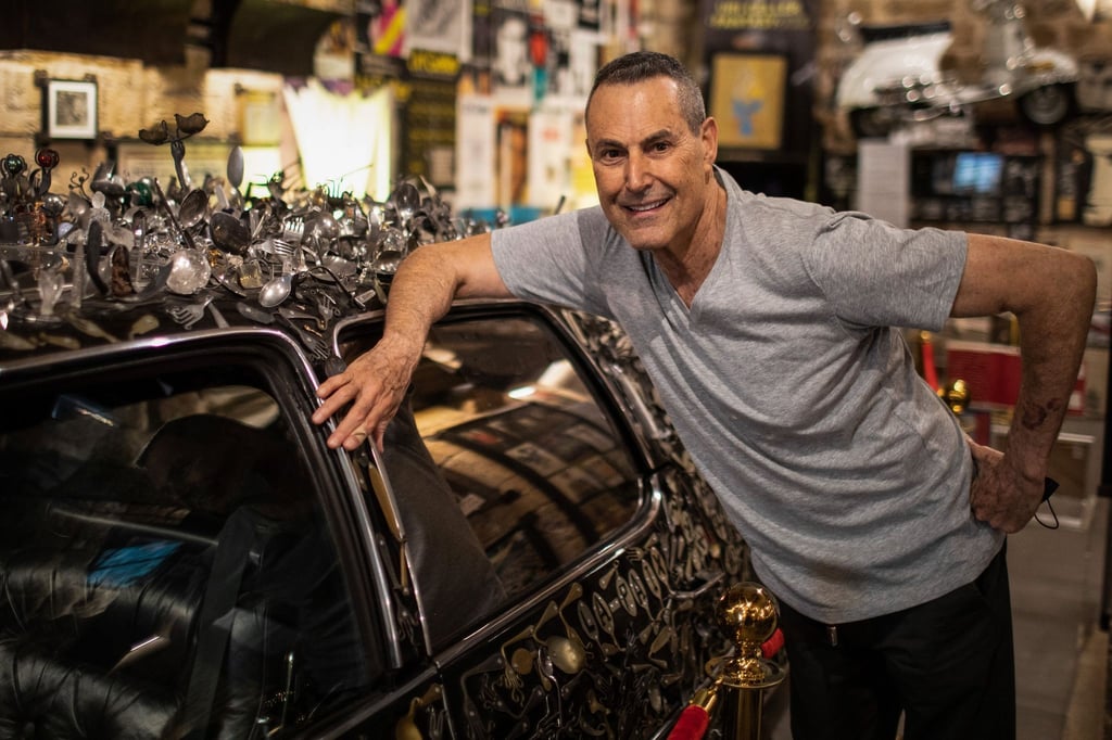 Uri Geller neben seinem mit verbogenem Besteck verzierten Cadillac.