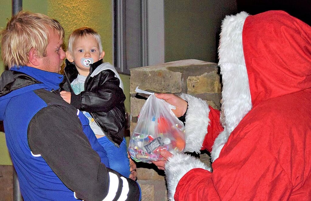 Jonah fühlte sich auf Papas Arm ganz sicher, als der Nikolaus zu ihm kam und ihm einen Beutel mit Süßigkeiten brachte.