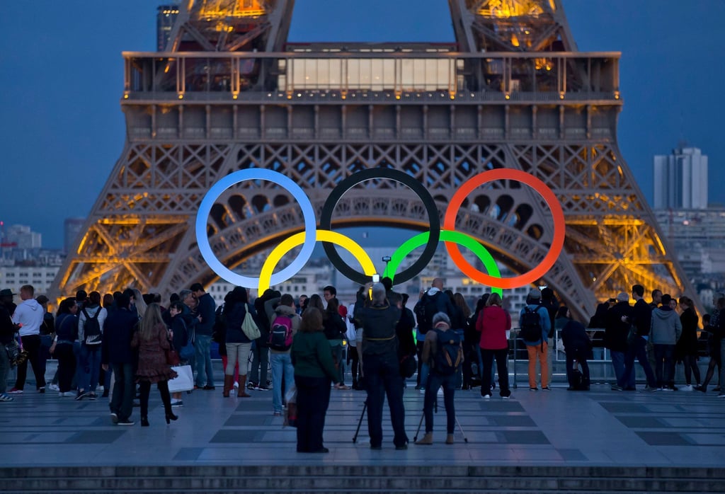 Die Olympischen Ringe leuchten am Fuße des Eiffelturms in Paris.