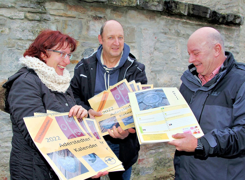 Ortsbürgermeister Mike Franzelius (r.) verteilt mit Jana und Bernd Scholz den neuen Aderstedt-Kalender.