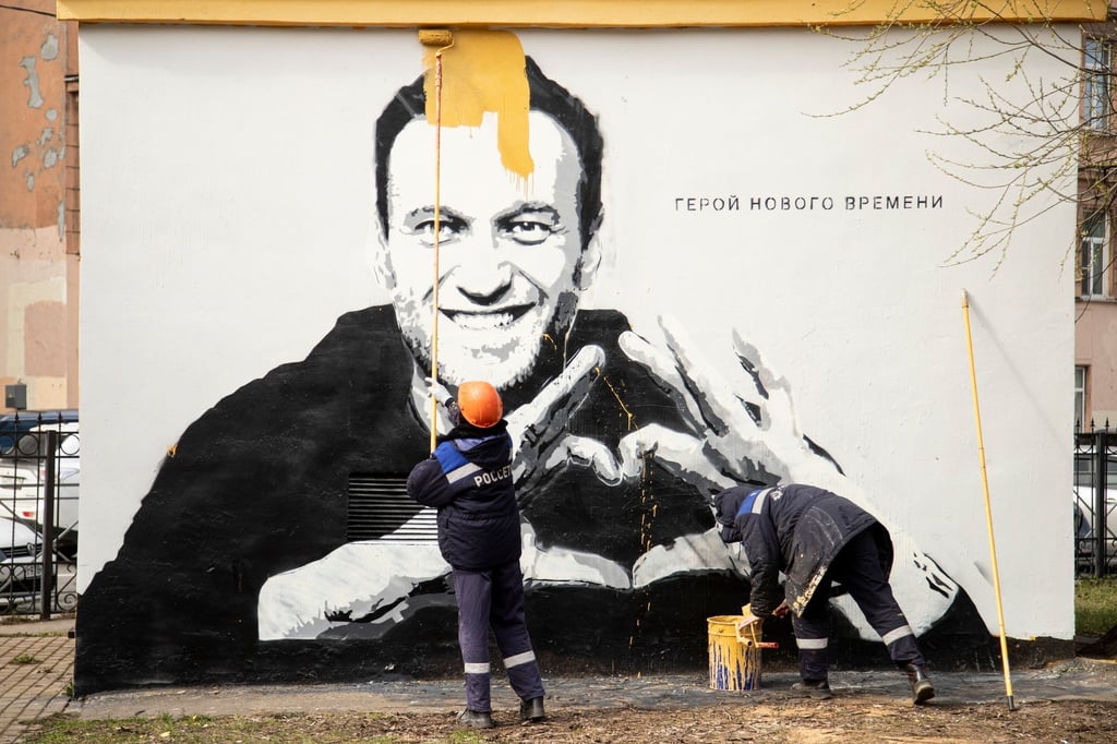 Städtische Arbeiter übermalen ein Graffiti mit dem Konterfei von Alexej Nawalny. Auf der Wand ist zu lesen: „Held unserer Zeit“.