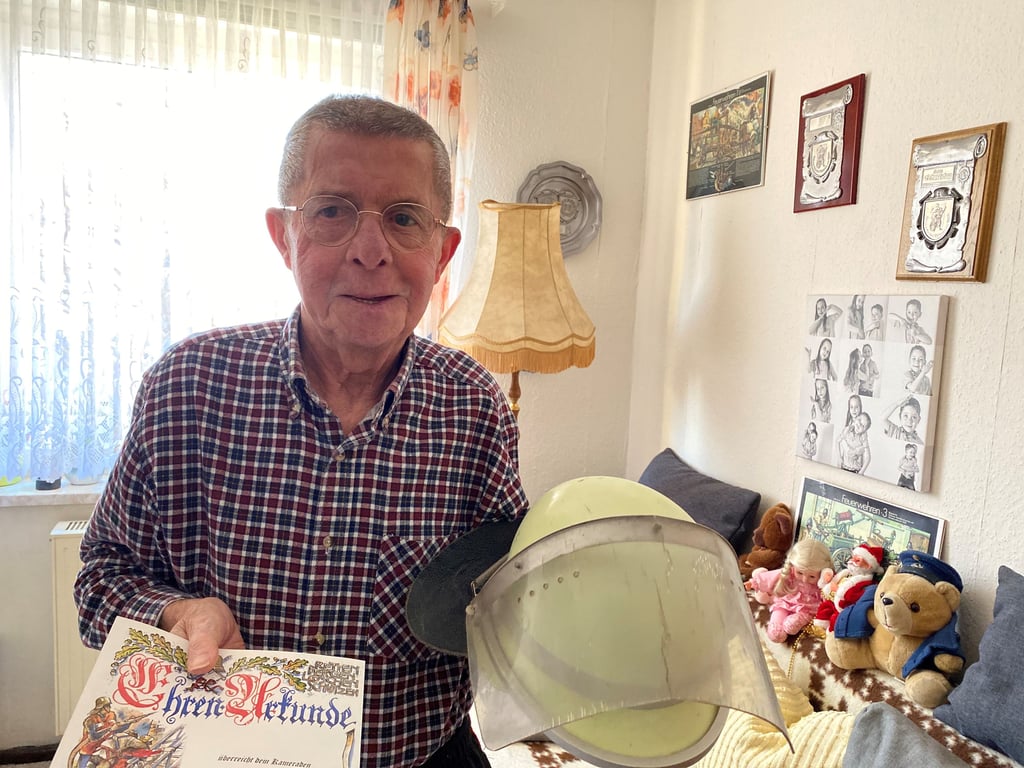 Achim Pätz mit seinem alten Einsatzhelm und der Ehrenurkunde für 70 Jahre Feuerwehr.