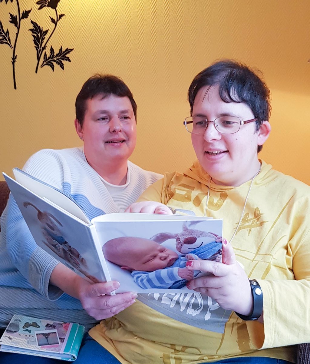 Betreuerin Manuela Sielaff schaut sich gemeinsam mit Bewohnerin Stephanie Mohaupt ein Familienfotoalbum an.