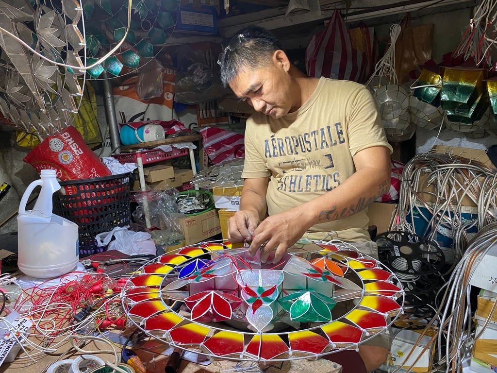 Andrew Flores fügt in seinem kleinen Geschäft für Weihnachtsdekoration im Dorf Elias Aldana nahe Manila Glühbirnen zu einer aus Capiz-Muscheln gefertigten Parole hinzu.