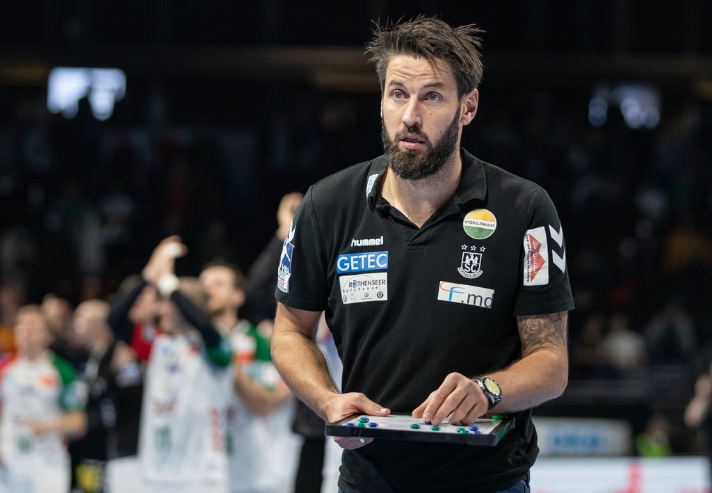 Magdeburgs Trainer Bennet Wiegert hält einen Spielplan in der Hand.