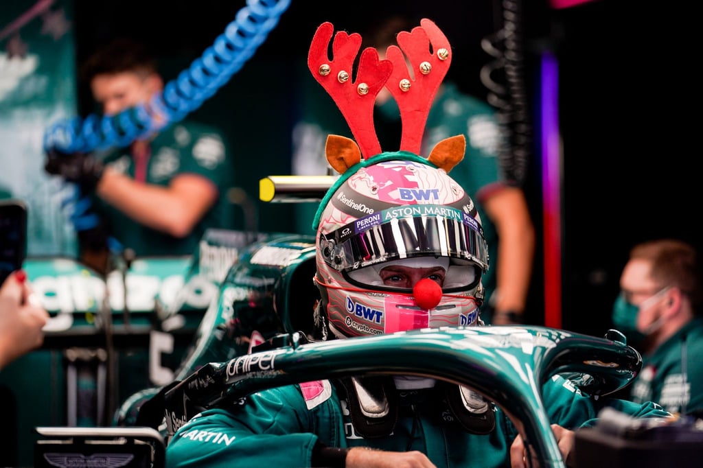 Rennfahrer Sebastian Vettel trägt bei einem Test für sein Team ein rotes Rentiergeweih und eine rote Nase am Helm.
