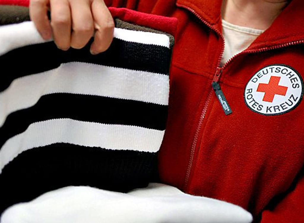Eine Mitarbeiterin des Deutschen Roten Kreuzes sortiert Pullover.