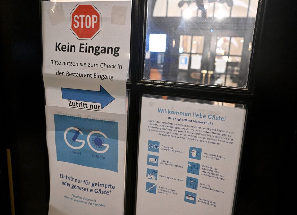 Diverse Schilder zum Einhalten der Corona-Schutzmaßnahmen hängen am Eingang zu einer Gaststätte.