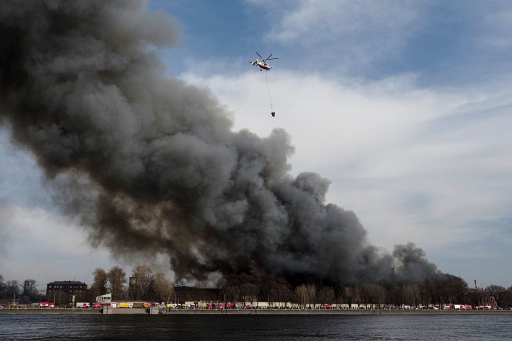 St. Petersburg: Ein Hubschrauber des russischen Katastrophenschutzministerium lässt Löschwasser über der brennenden Nevskaya Manufaktura Textilfabrik am Oktjabrskaja-Ufer an der Newa ab.