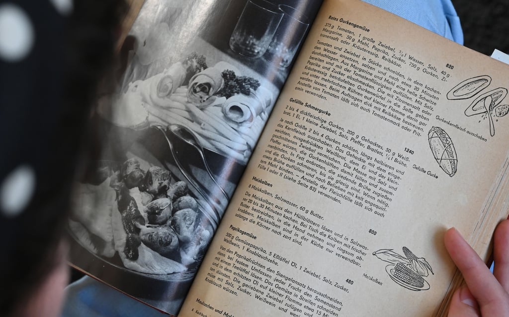 Ein Teenager blättert in dem Buch "wir kochen gut" aus den 60er Jahren.