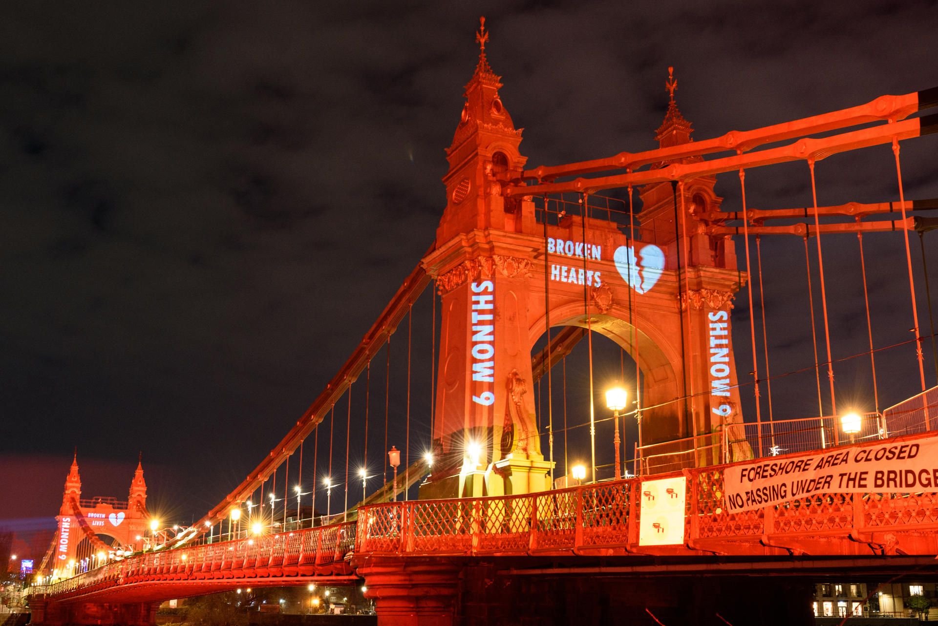 Die Hammersmith-Brücke zeigt, die für den Valentinstags hellrot beleuchtet wurde, um auf die anhaltenden Verzögerungen bei der Reparatur hinzuweisen.