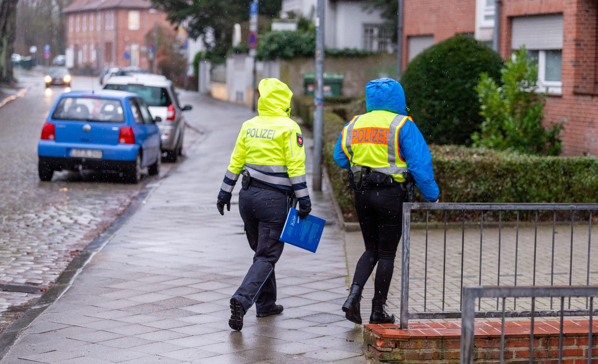 Polizisten gehen in der Nähe des Parkplatzes, auf dem eine Frauenleiche in einem Auto gefunden wurde, von Haus zu Haus und befragen Anwohner nach Zeugenhinweisen.