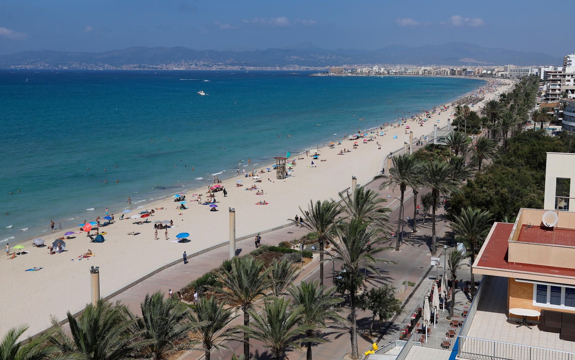Menschen sonnen sich und schwimmen am Strand von Arenal auf Mallorca.