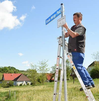 Gemeindearbeiter Ralf Schumann montiert das neue Straßenschild.