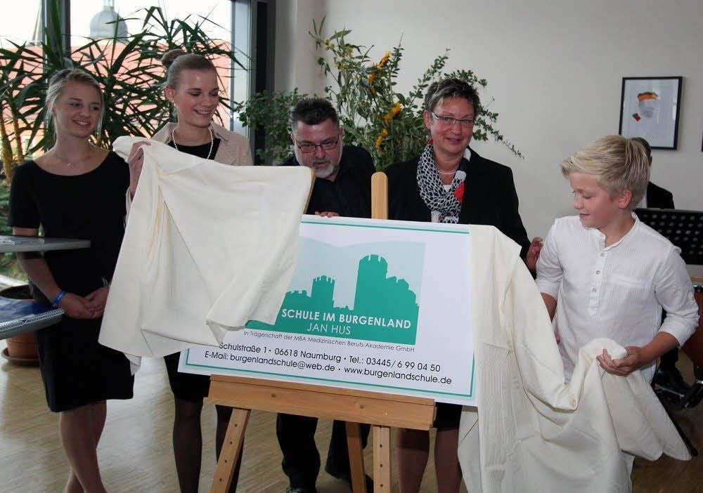 Gemeinsam mit Schulleiterin Kathrin Wahlbuhl-Nitsche und MBA-Dozent Ronald Schulz enthüllen die Schüler Sophia Dorn, Lena Hempel und Mou Herrmann nach der feierlichen Namensgebung das neue Logo der Naumburger Freien Schule im Burgenland Jan Hus.