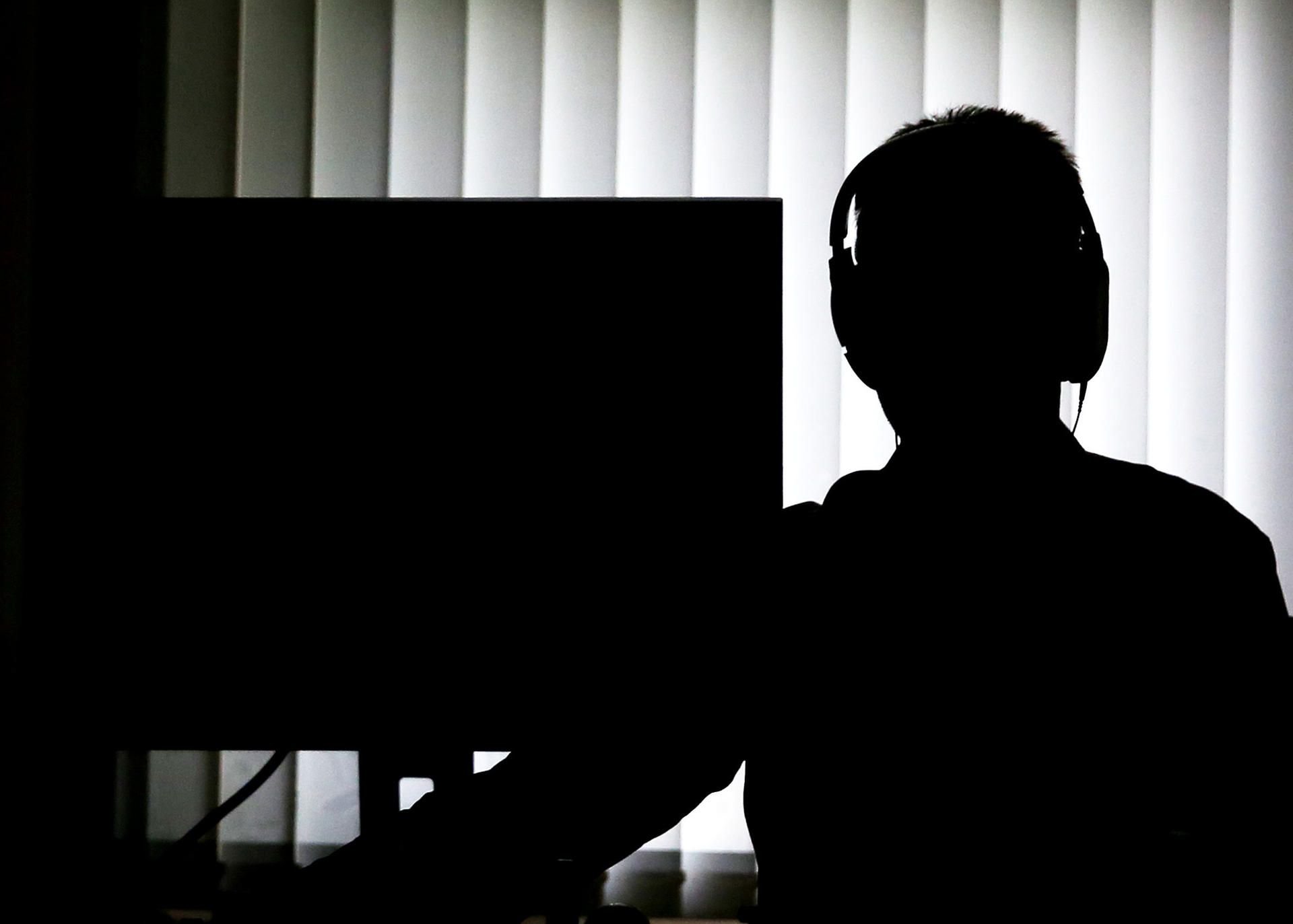 Illustration: Ein Beamter sitzt mit Kopfhörern vor einem Computer in einem Büro. Aus einer Datenbank der Polizei sind versehentlich rund 42 000 Datensätze zu Straftätern aus Sachsen-Anhalt gelöscht worden - die Rettung ist aber wahrscheinlich.