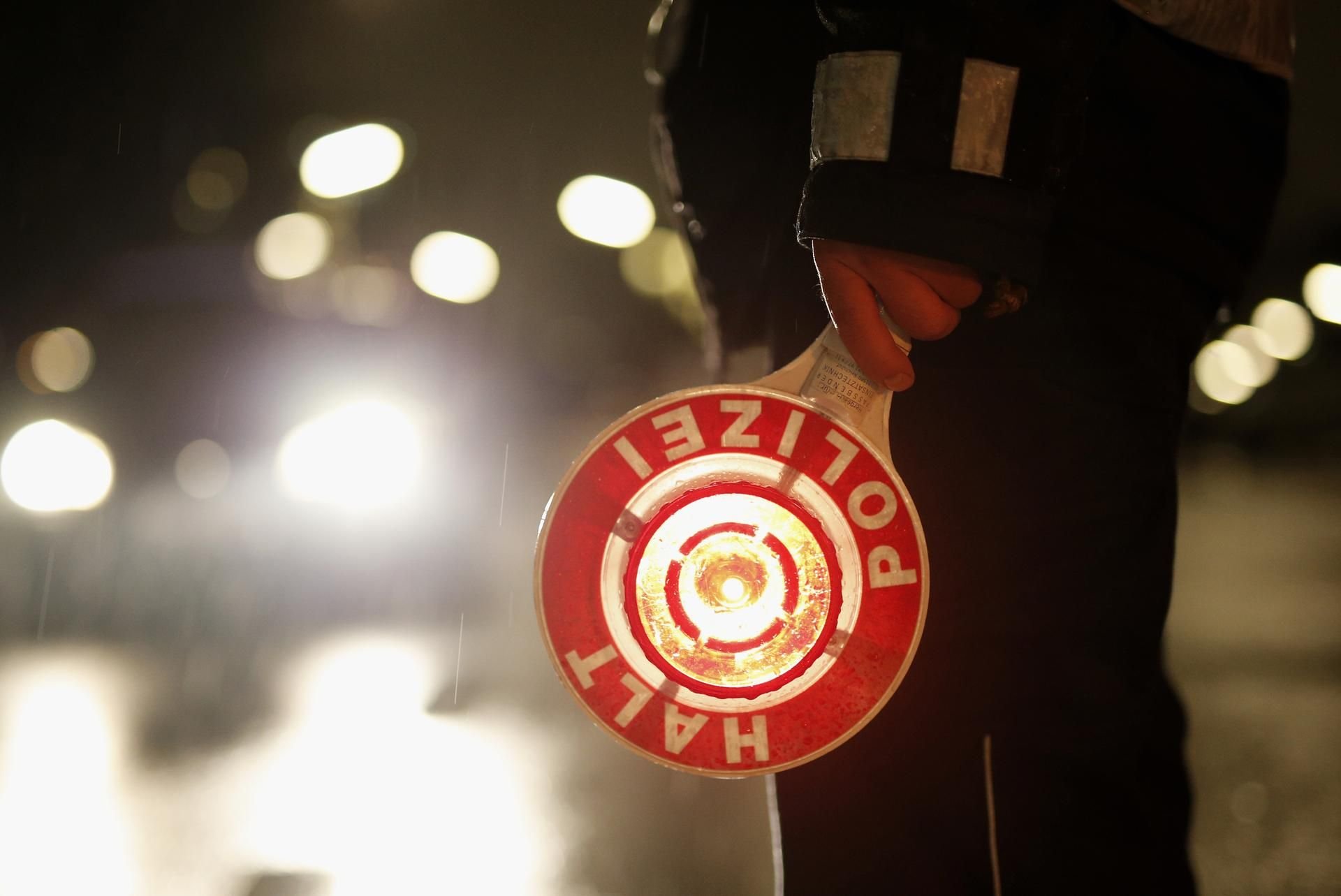 Ein Polizeibeamter hält während einer Verkehrskontrolle eine Kelle in der Hand.