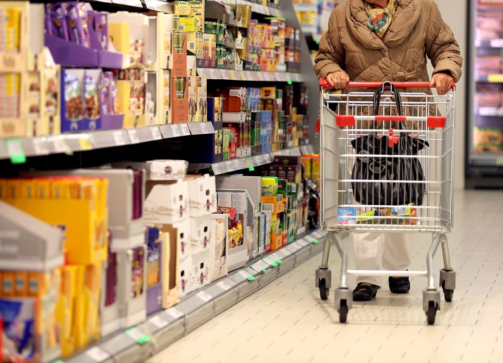 Eine Kundin schiebt ihren Einkaufswagen durch einen Supermarkt.