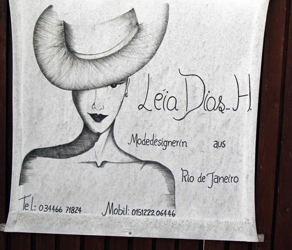 Ins Auge fallend an einem Hoftor in Meyhen: Handgezeichnet blickt da eine Frau mit einem modisch-eleganten Hut mit breit geschwungener Krempe von einem Poster. Die Aufschrift macht natürlich zusätzlich neugierig.