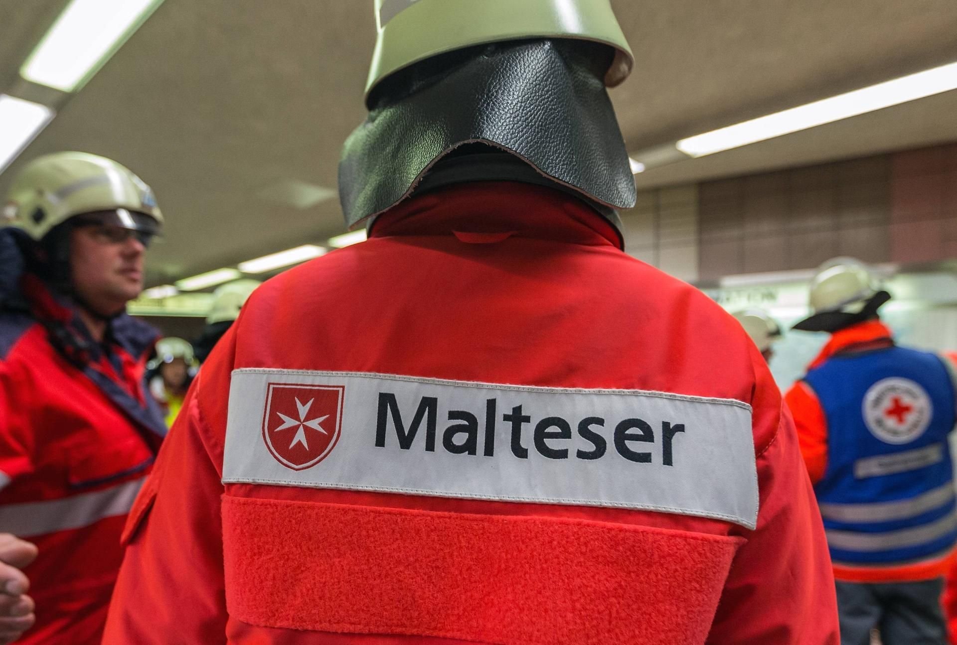 Schritzug Malteser auf dem Rücken eines Helfers (Symbolbild)