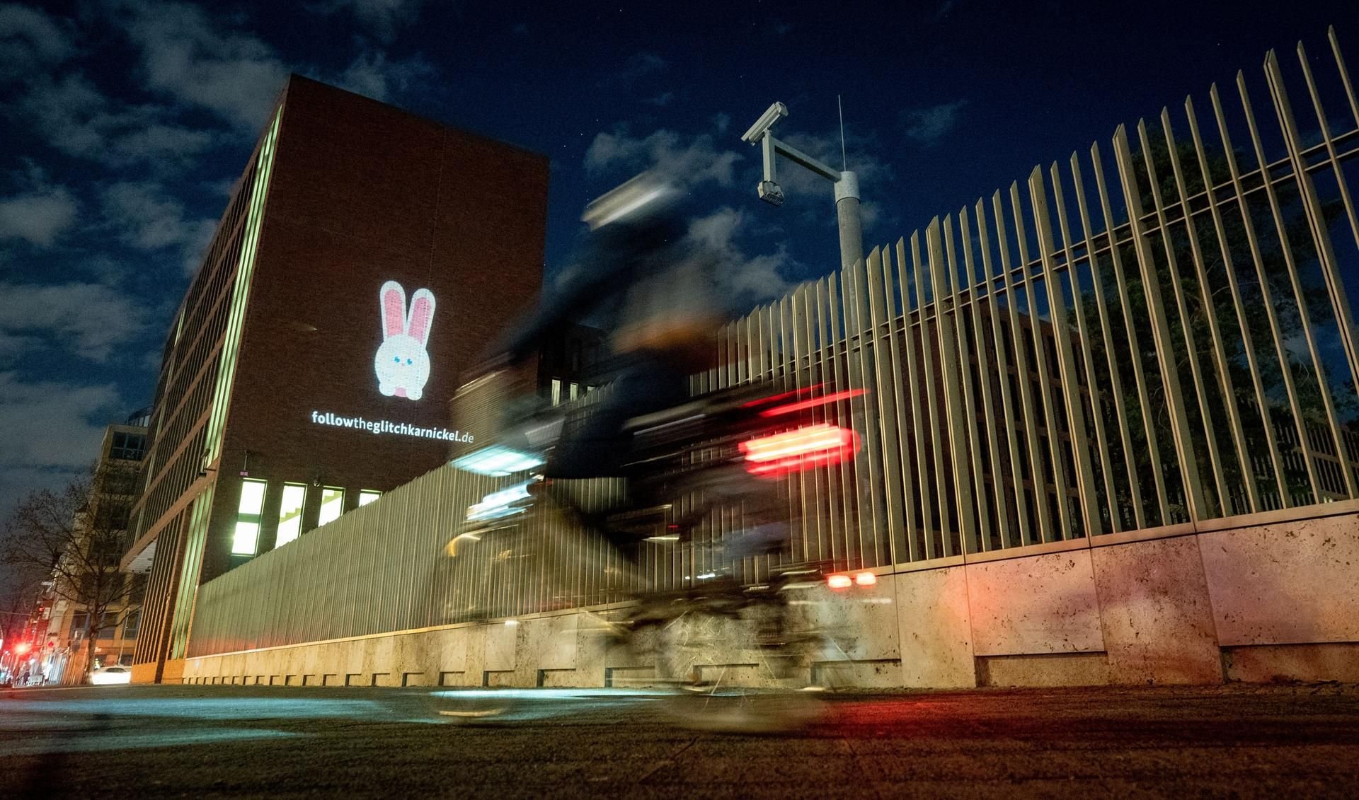 Ein Hase wird auf die Fassade der Zentrale des Bundesnachrichtendienstes (BND) projiziert. Unter dem Hasen ist die Internetadresse "followtheglitchkarnickel.de" zu sehen.