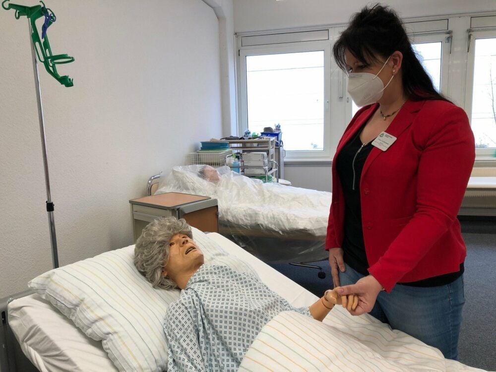 Leiterin Sabine Kellermann steht im Praxisraum an einer Geriatrie-Puppe, an der die Pflegekräfte ausgebildet werden.