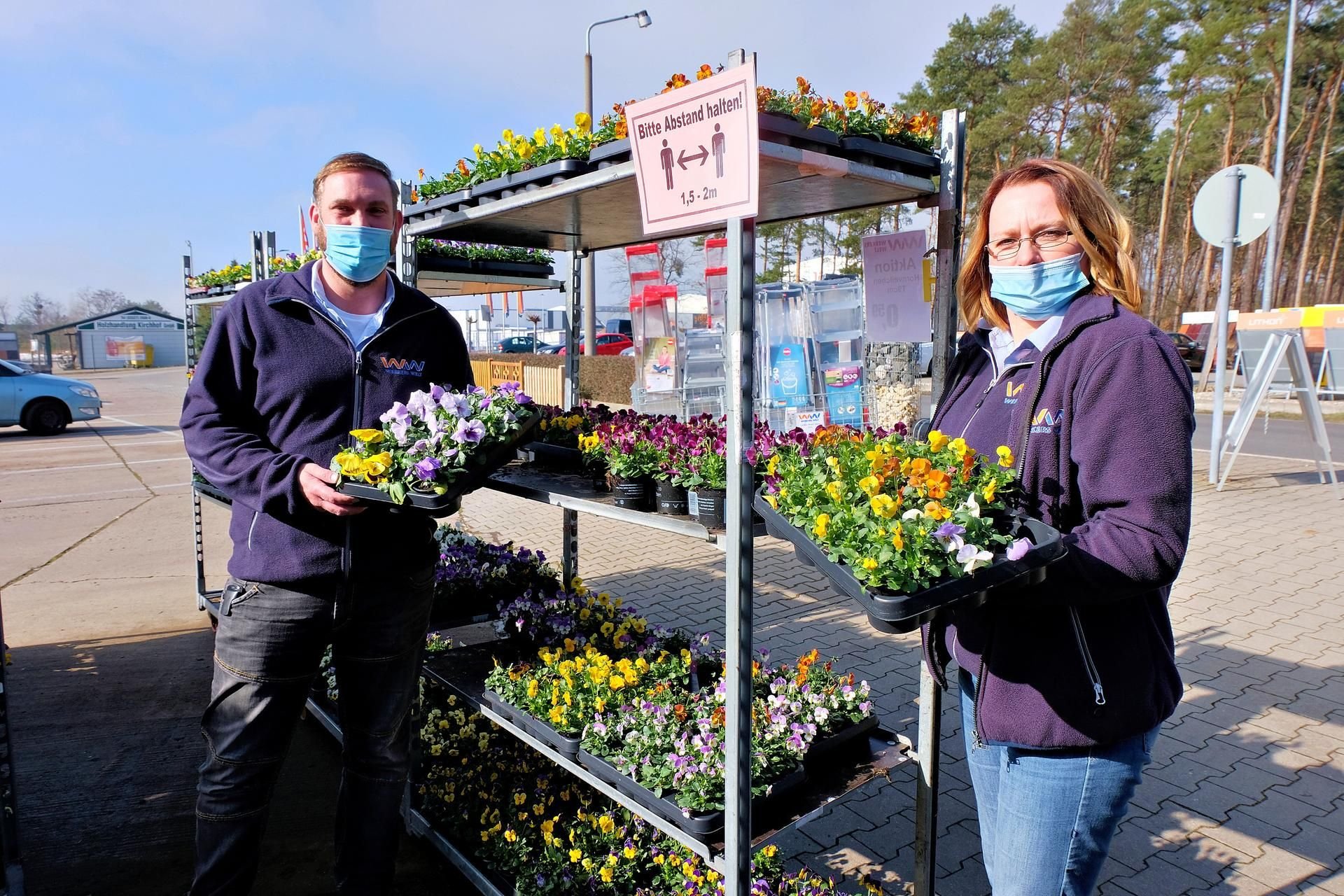 Marktleiter Marcel Schlobach und Mitarbeiterin Katrin Walder präsentieren die ersten Frühblüher vor dem Baumarkt Wittig in Jessen.