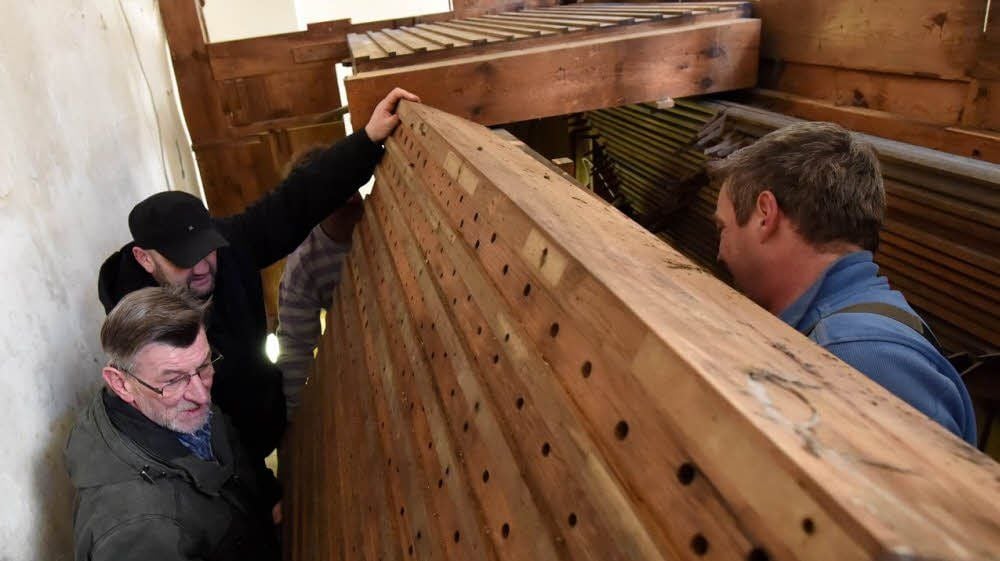 Mit Hilfe der Flemminger Joachim Vogel und Hagen Seitz (v. l.) werden die zwei rund 250 Kilogramm schweren Windladen der Orgel ausgebaut und zur Restaurierung zur Firma Bochmann, hier Christian Bochmann (r.), gebracht.