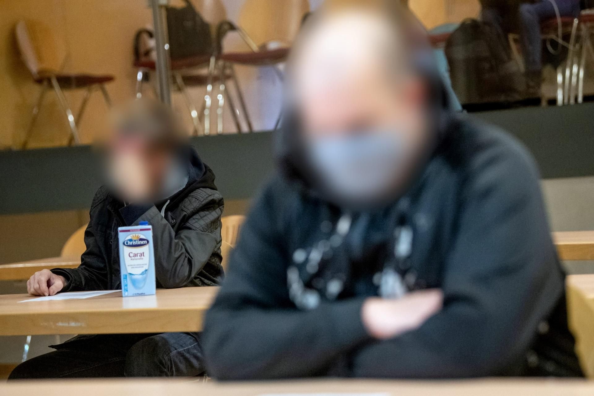Zwei der Angeklagten sitzen vor Prozessbeginn in der Stadthalle Verden. Drei Angeklagte sollen eine 19-Jährige gefesselt und mit einer Betonplatte lebend in der Weser versenkt haben.