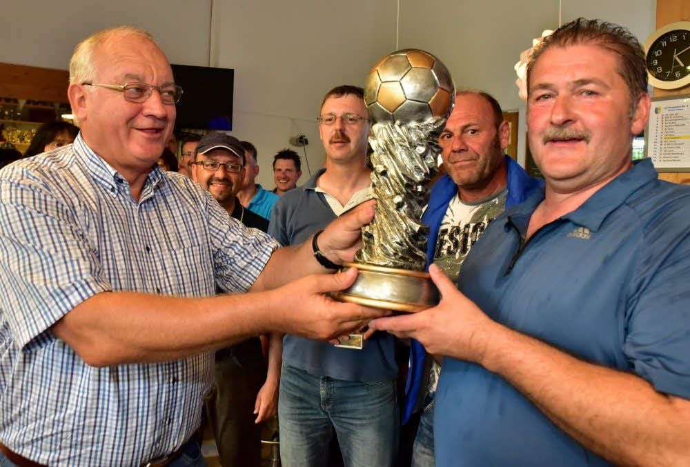 Harri Reiche übergibt den von Landrat Götz Ulrich gestifteten Siegerpokal an Thomas Ratzka vom Wirtschaftsteam.