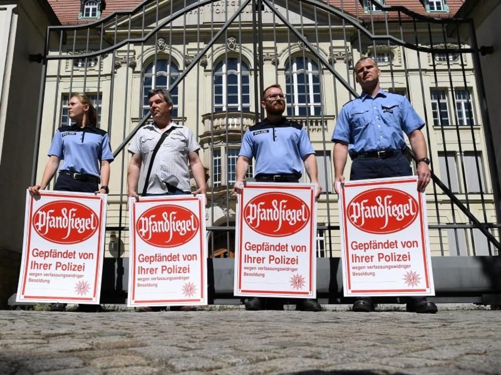 Mit symbolischen Pfandsiegeln protestieren Polizisten an der Pforte der Brandenburger Staatskanzlei für eine Nachzahlung der Mindestbesoldung. Foto: Ralf Hirschberger
