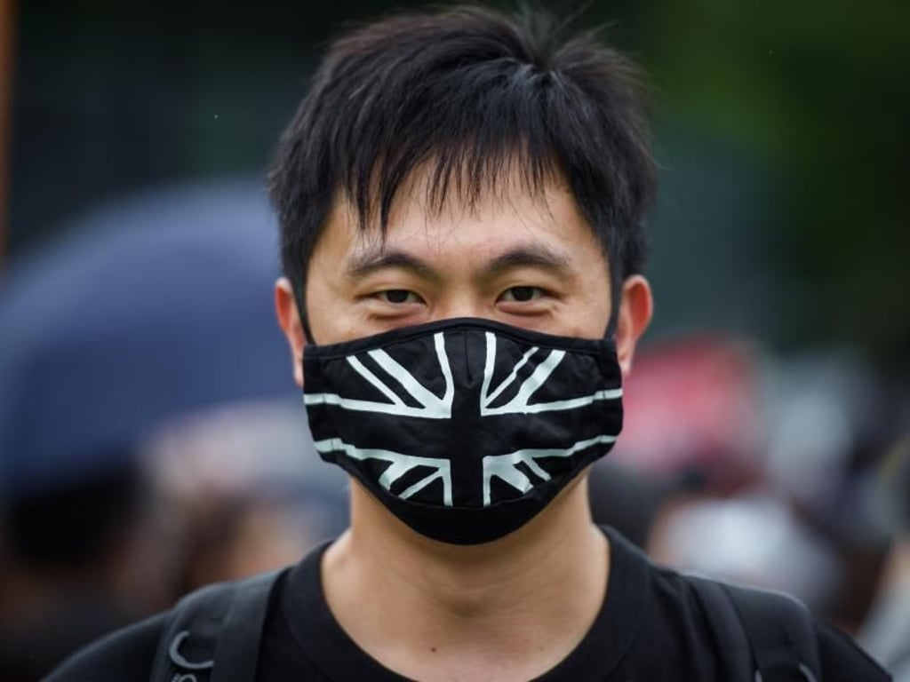 Ein Teilnehmer der Protestkundgebung trägt auf dem zentralen Ort der Kundgebung im Victoria Park einen Mundschutz mit der britischen Flagge. Foto: Gregor Fischer