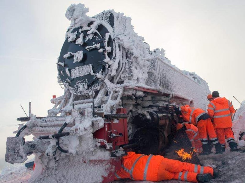Arbeiter enteisen auf dem Brocken Fahrwerksteile, um den Zug nach der langen Standzeit bewegen zu können. Foto: Klaus-Dietmar Gabbert/Archiv