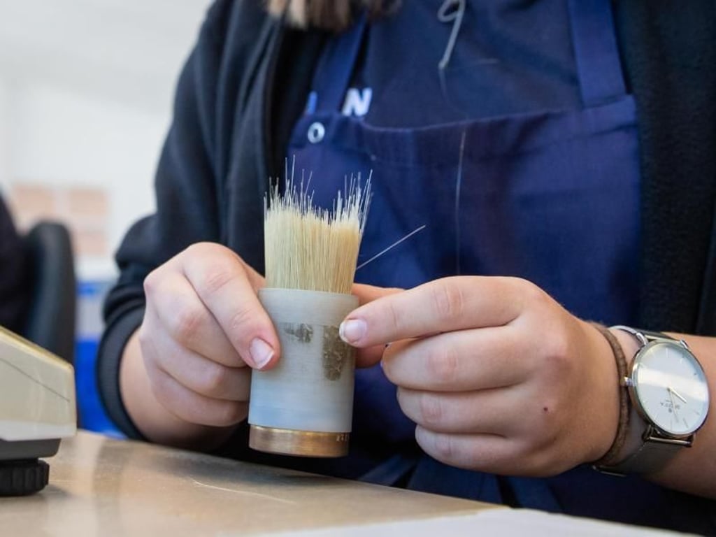 Manchmal brauchen Pinsel- und Bürstenmacher auch etwas Kraft. Azubi Kristina Bauer klopft eine Formhülse mit Borsten auf den Tisch. Foto: Daniel Karmann