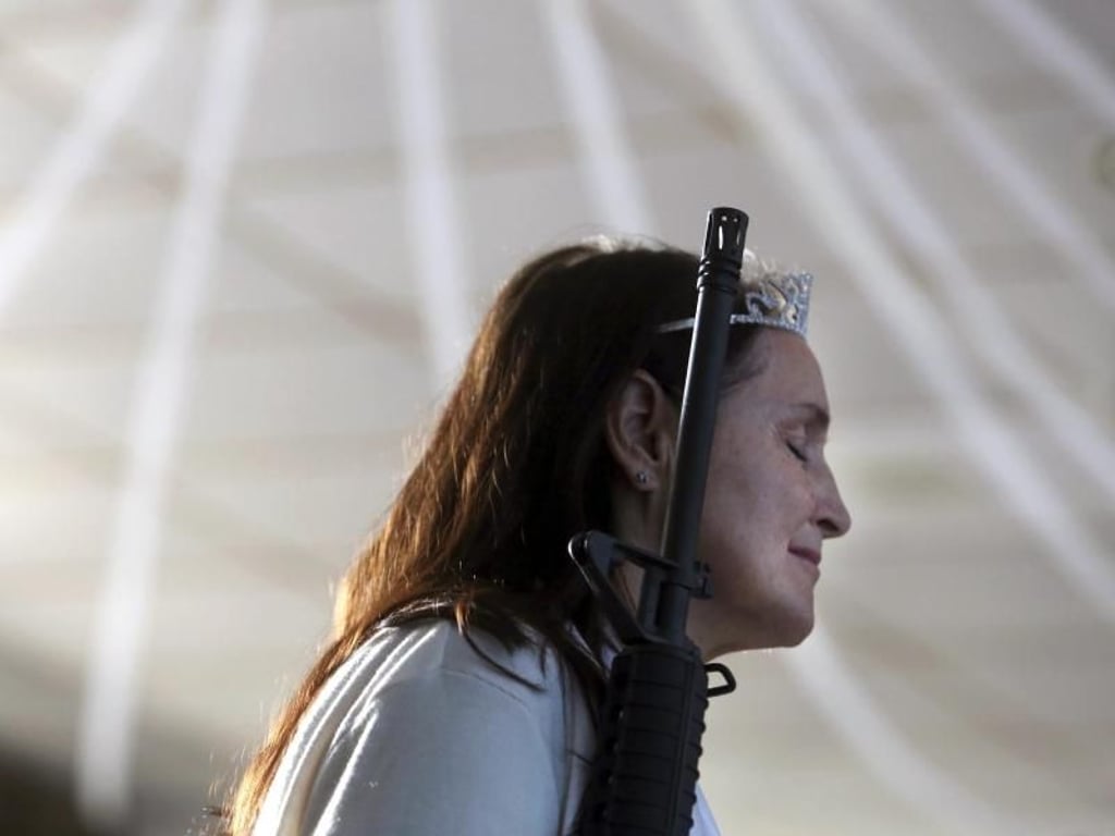 In religiöser Verzückung: Mit geschlossenen Augen schmiegt sich eine Frau beim Gottesdienst an ihr AR-15-Gewehr. Foto: Jacqueline Larma/AP