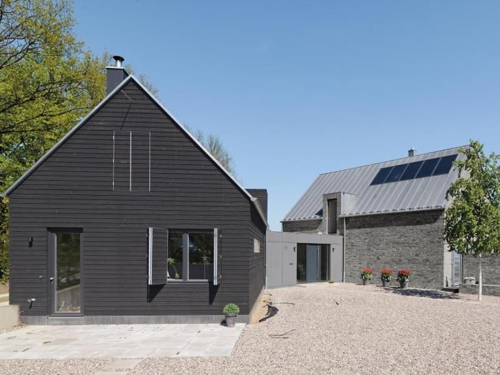 An regionale Bauernhöfe der Holsteinischen Schweiz angelehnt plante der Architekt dieses moderne Wohnhaus. Die beiden Baukörper sind miteinander verbunden: Das Wohnhaus (r) trägt eine typisch norddeutsche Ziegelfassade, das Nebenhaus mit Werkstatt, Lager und Ferienwohnung hat wie viele alte Scheunen eine mit Teerfarbe gestrichene Fassade aus Fichte. Foto: Johannes Kottjé/Mißfeldt Kraß Architekten/dpa-tmn