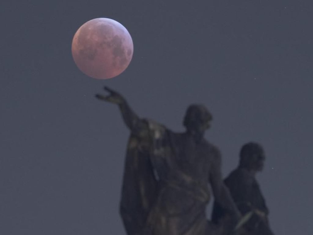 Der Vollmond zeigt sich hinter einer Mattielli-Statue in Dresden, während er in den Kernschatten der von der Sonne angestrahlte Erde tritt. Foto: Sebastian Kahnert