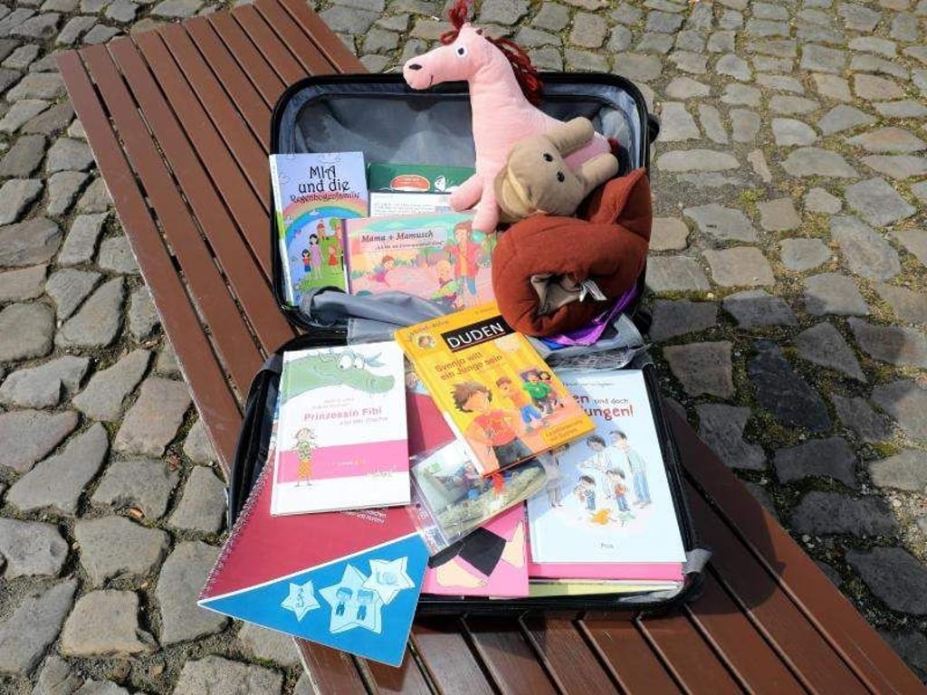 Ein geöffneter Medienkoffer mit Büchern und Spielen liegt auf einer Bank. Foto: Peter Gercke