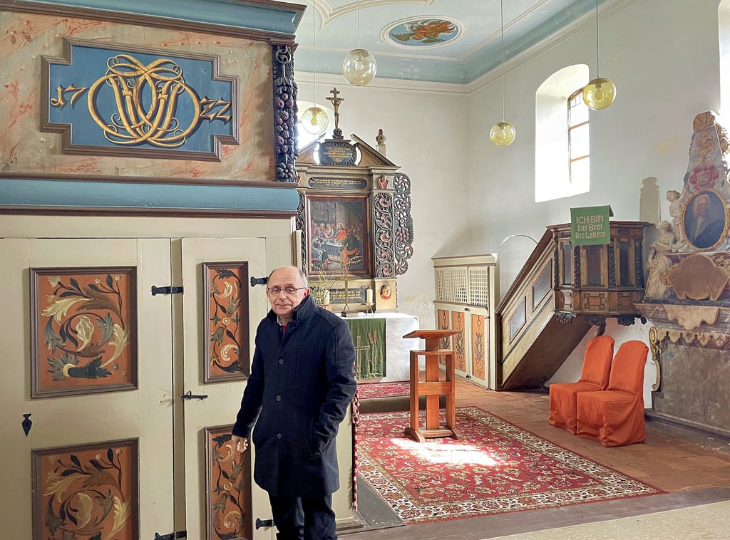 Pfarrer Georg Strutz in der Brietzker Kirche. Über der Holztür ist das Jahr des Kirchenbaus 1722 reich verziert angegeben. Auch im Innenraum stehen Malerarbeiten an. Sie sollen bis zum Jubiläum fertig sein.