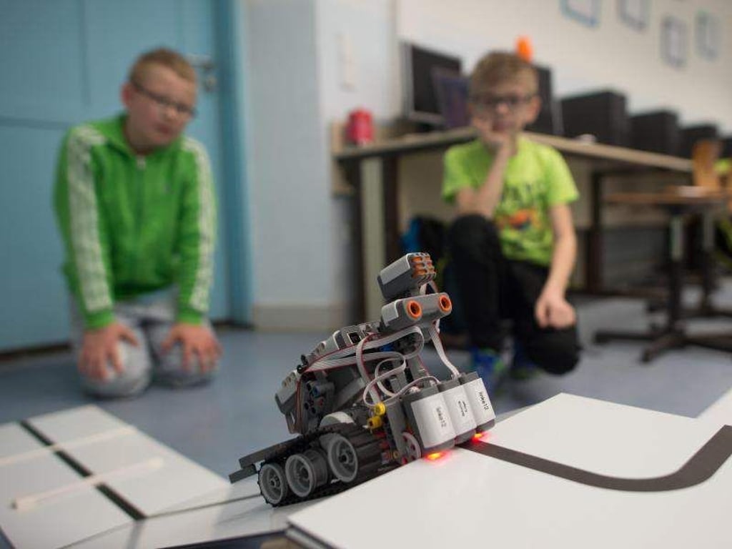 Zwei Kinder beobachten ihren selbstgebauten Rettungs-Roboter beim Durchfahren eines Parcours. Foto: Klaus-Dietmar Gabbert