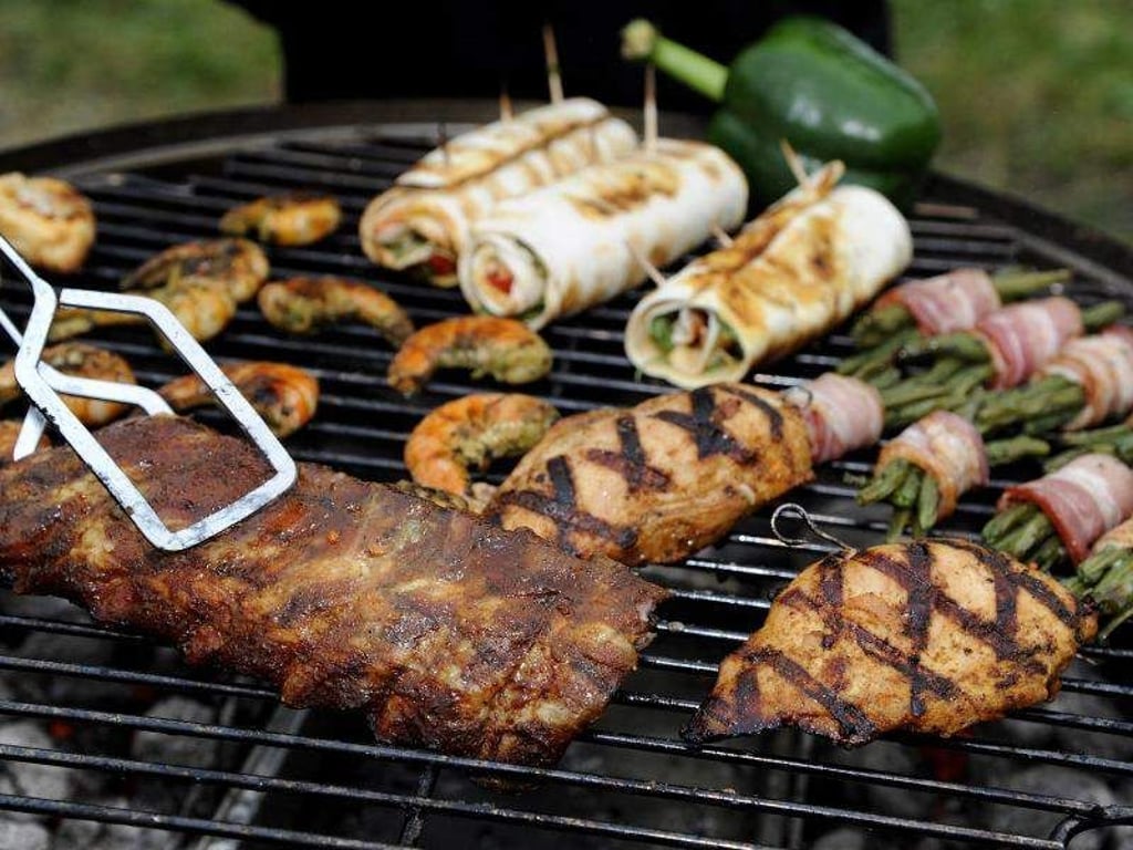Spareribs, Gemüse, gefüllte Hühnerbrust und Garnelen liegen auf dem Grill. Foto: Daniel Maurer