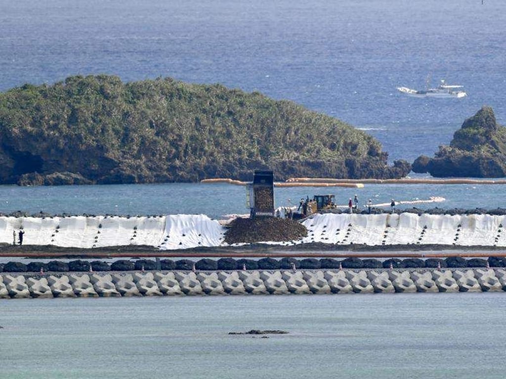 Ein Lkw kippt vor Nago Erdmassen zur Landgewinnung ins Meer. Foto: kyodo