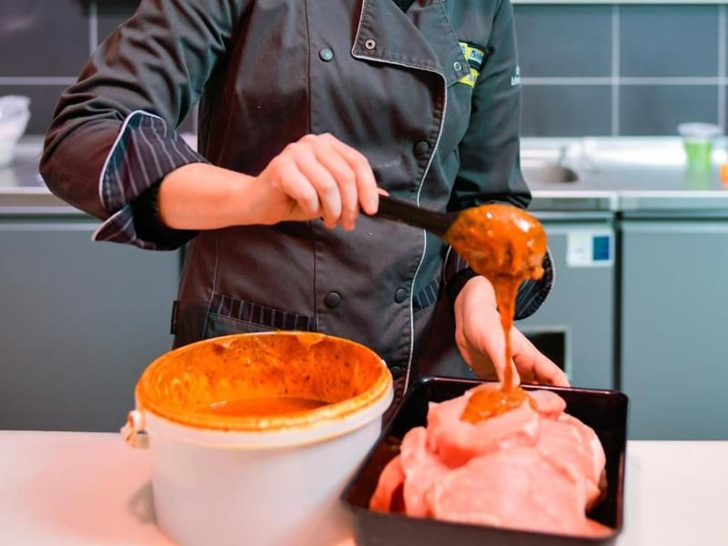 Vor dem Verkauf mariniert die Auszubildende Diana Kari das Fleisch. Zum Teil bereiten Fachverkäufer im Lebensmittelhandwerk kleinere Speisen, Imbisse oder Getränke auch selbst zu. Foto: Uwe Anspach