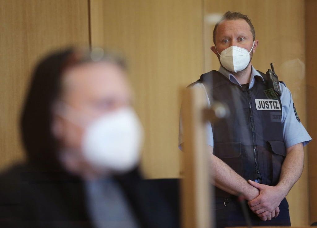 Der Angeklagte (links) sitzt im Gerichtssaal vor Justizangestellten. Fast ein Vierteljahrhundert nach dem Auffinden eines getöteten Mannes hat der Mordprozess gegen einen 51-Jährigen begonnen.