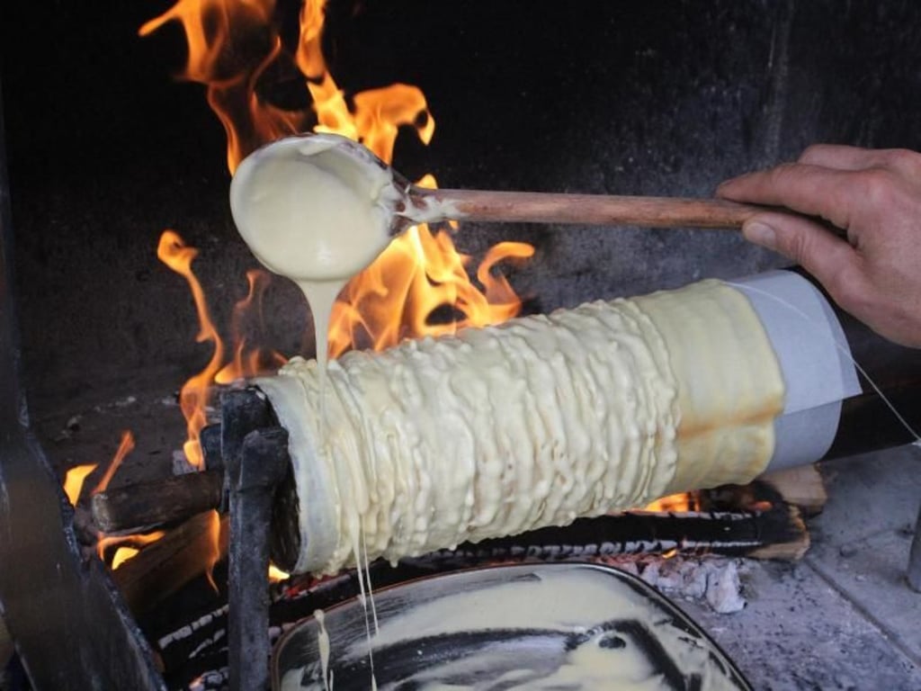 Da ist eine ruhige Hand gefragt: Der Teig muss beim Backen der Prügeltorte über dem offenen Feuer dosiert aufgetragen werden. Foto: Bernd F. Meier