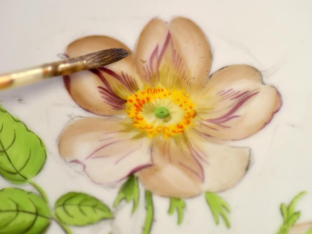 Ein feines Blumenmuster ziert einen Teller: Manufakturporzellanmaler tragen solche Dekore mit feinen Pinseln auf Keramikgeschirr auf. Foto: Matthias Rietschel